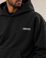 Close view of the small off-white BMV101 identifier on the black hoodie’s left chest