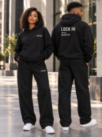 Two models in black hoodie and straight-leg sweatpants, showing front identifiers and the hoodie back print